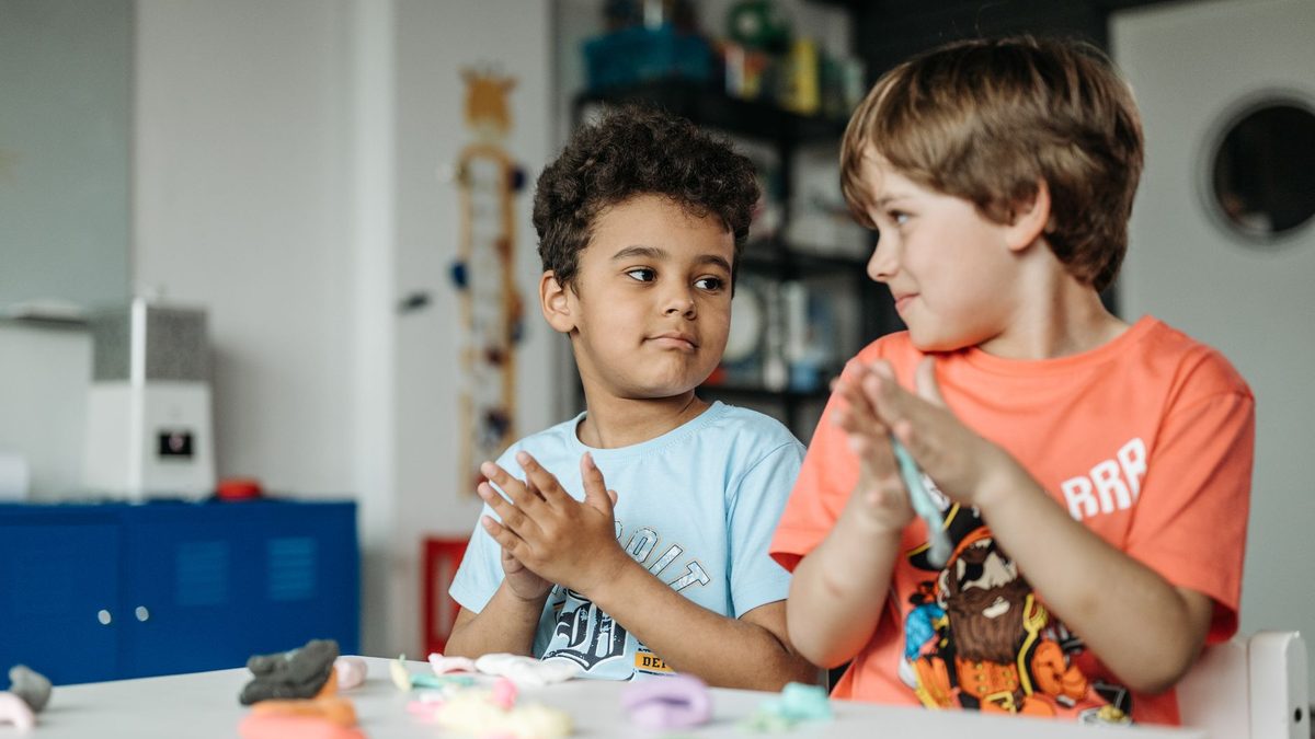 Two children facing each other across a desk