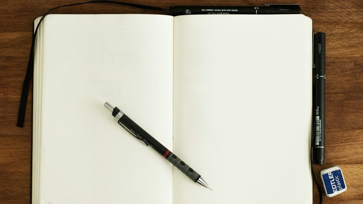 An open sketchbook with drawings and a pencil beside it