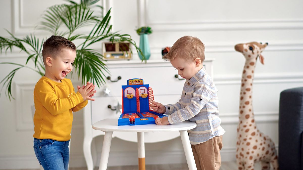 Two young boys playing a tabletop game against each other indoors
