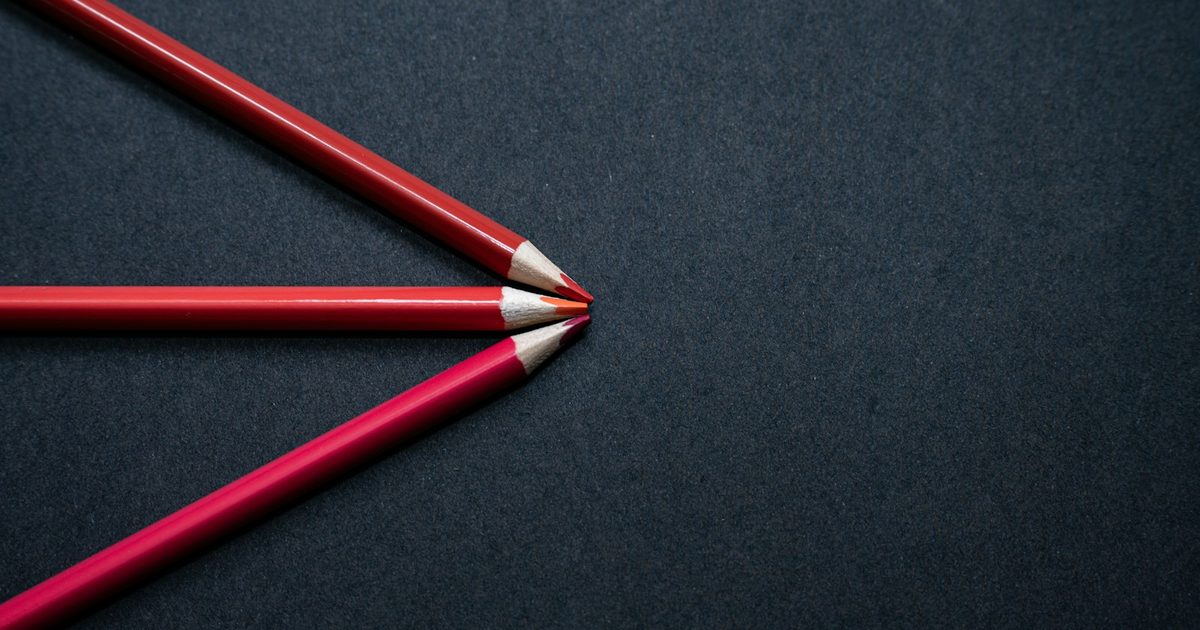 Two red pencils lying side by side on a black surface