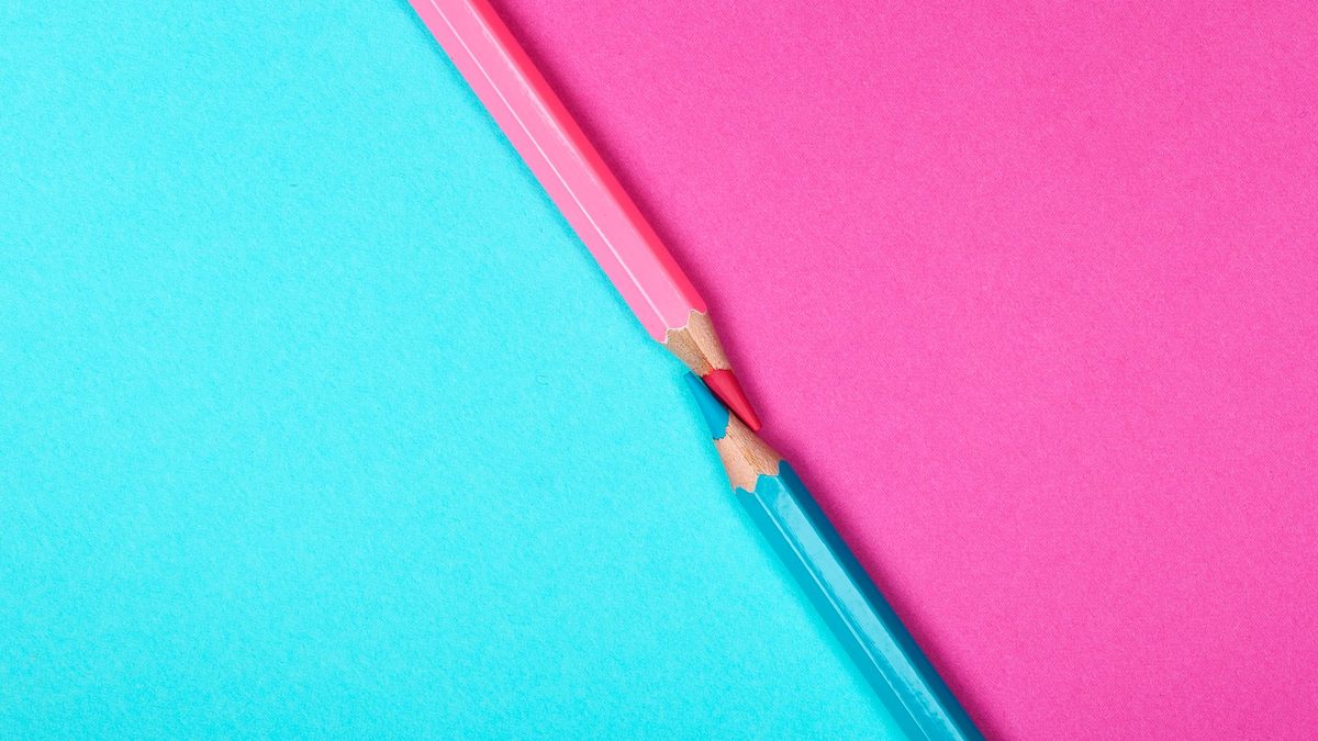 Two sharpened coloured pencils meeting on contrasting pink and blue paper