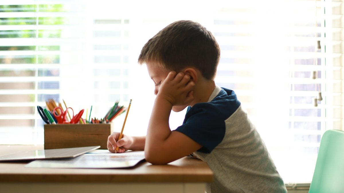 A young boy sitting at a desk working through a written worksheet
