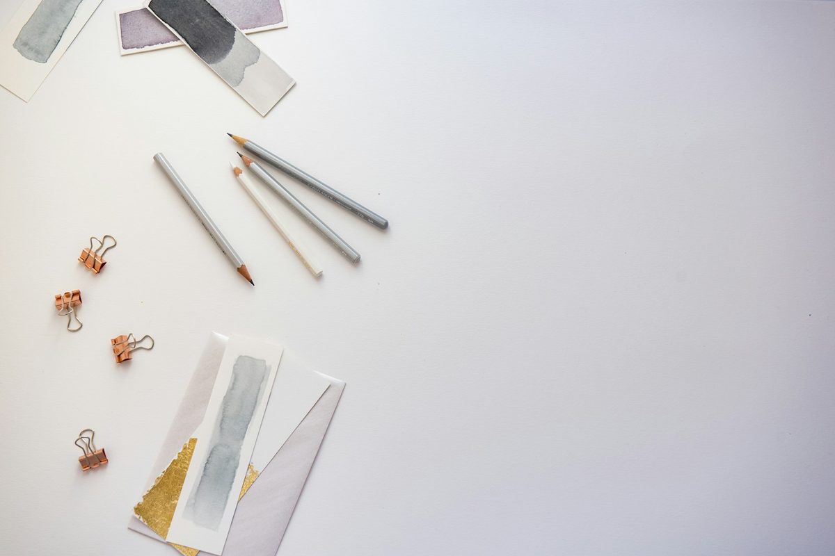 Paper clips, pencils and small stationery items laid out on a pale desk