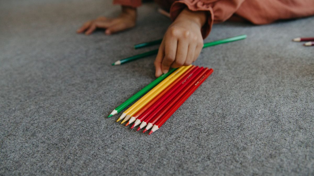 A child holding a collection of different pencils for trading