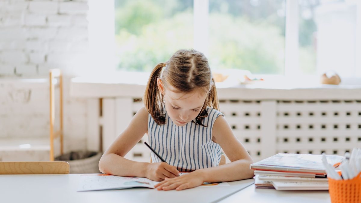 A child sitting comfortably at a table while writing