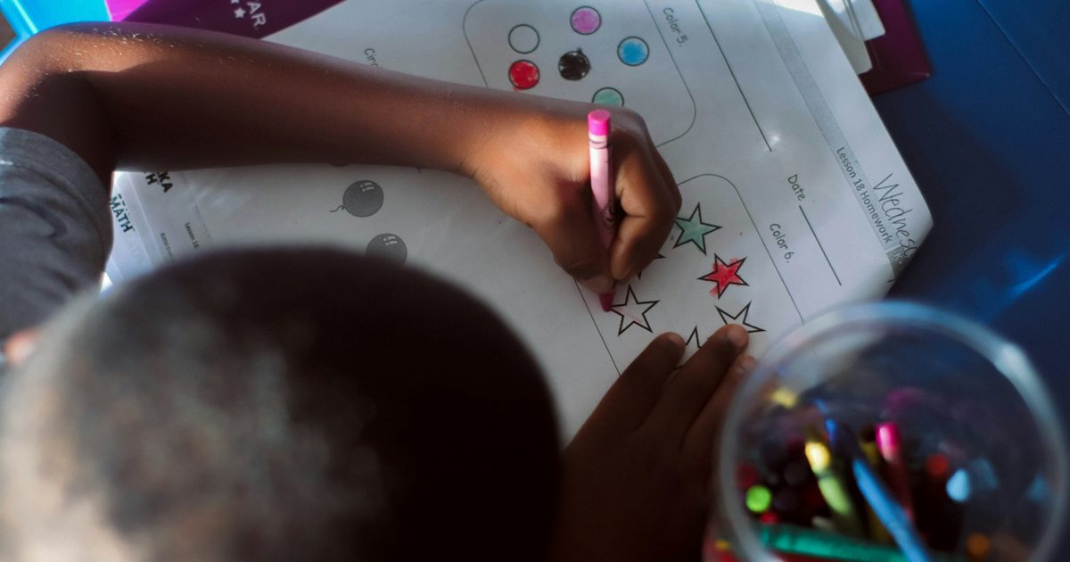 A child drawing with a pencil at a table