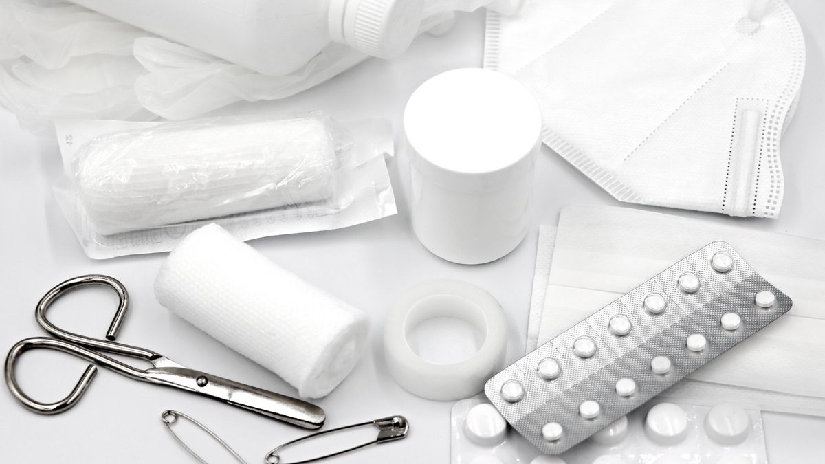A flat lay of first aid supplies and basic medical equipment on a white background