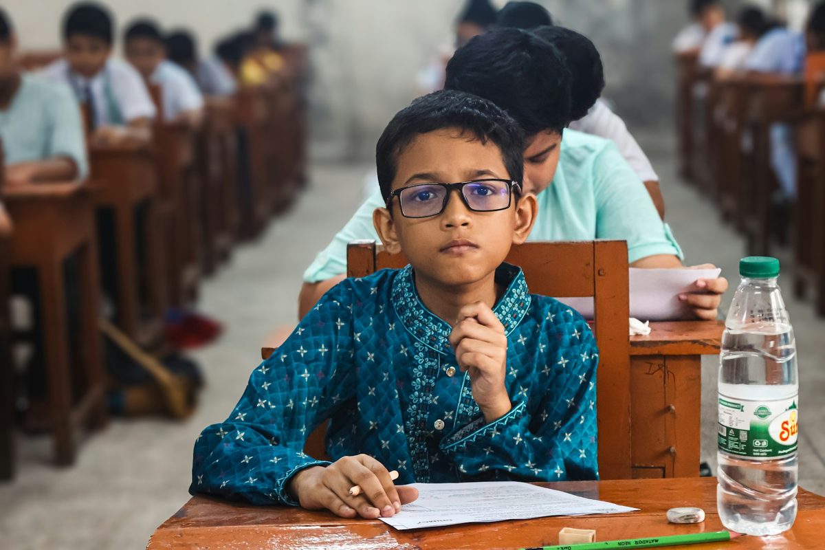 A pupil working at a desk with a small object held in one hand