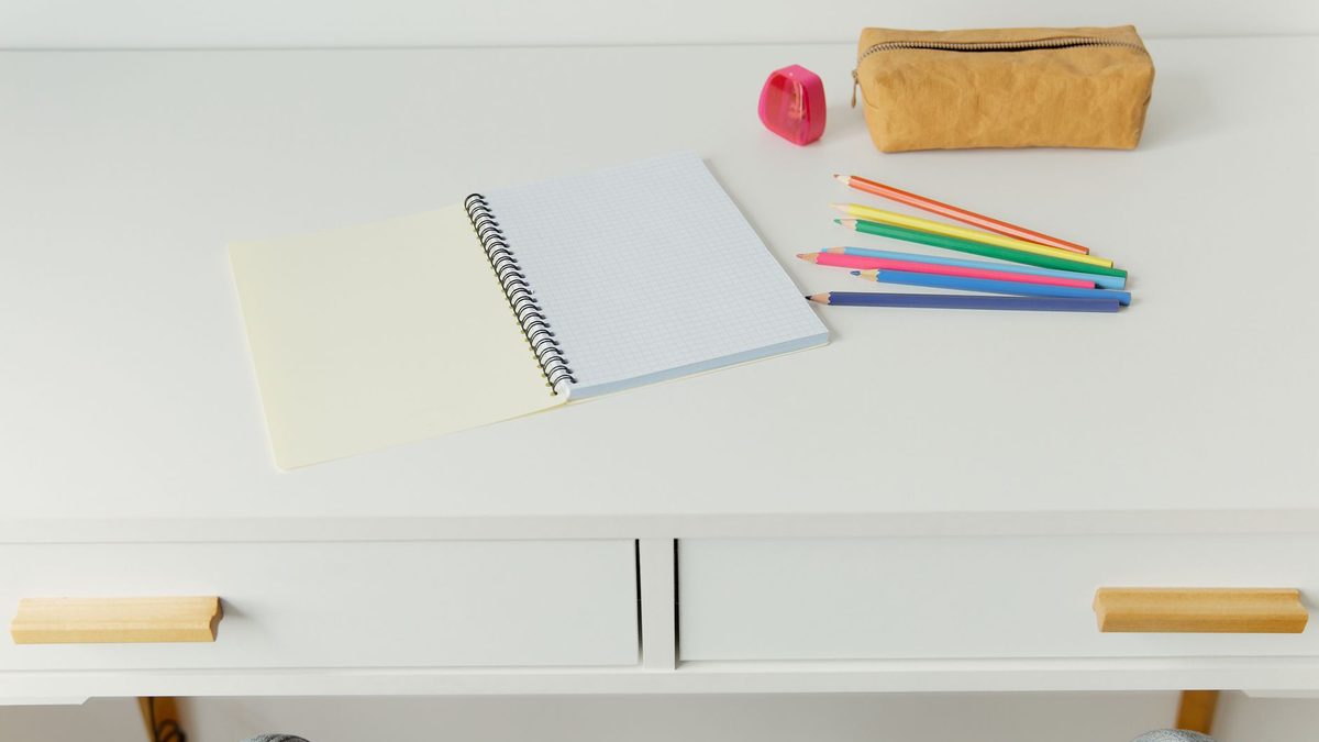 An open school pencil case with its contents on a desk