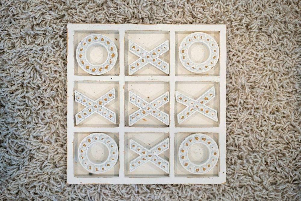 A wooden noughts and crosses board with X and O tiles placed in the grid