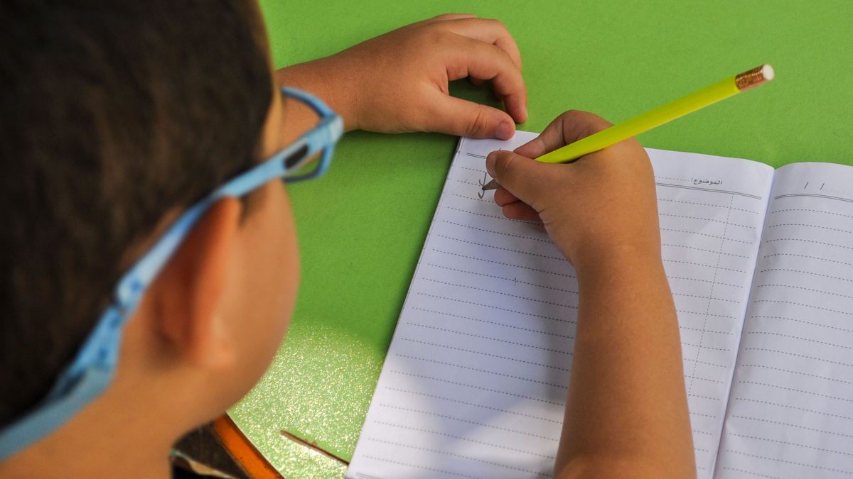 A child practising handwriting and forming letters on paper