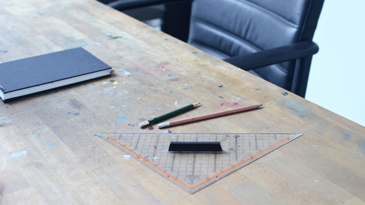 Notebook, pencils and a ruler laid out on a wooden desk, the everyday kit a pencil fight was played with