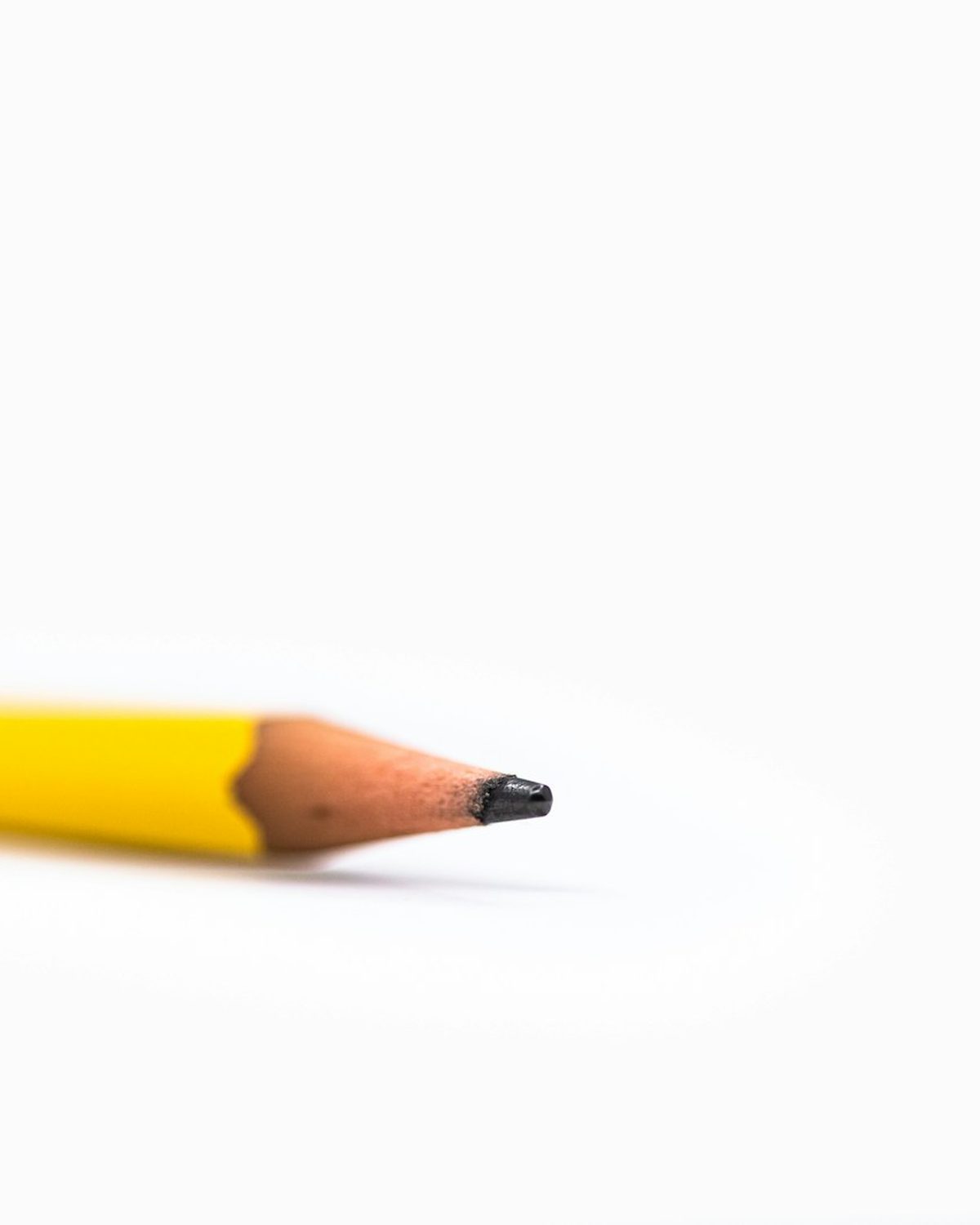 A yellow pencil lying on a clean white surface