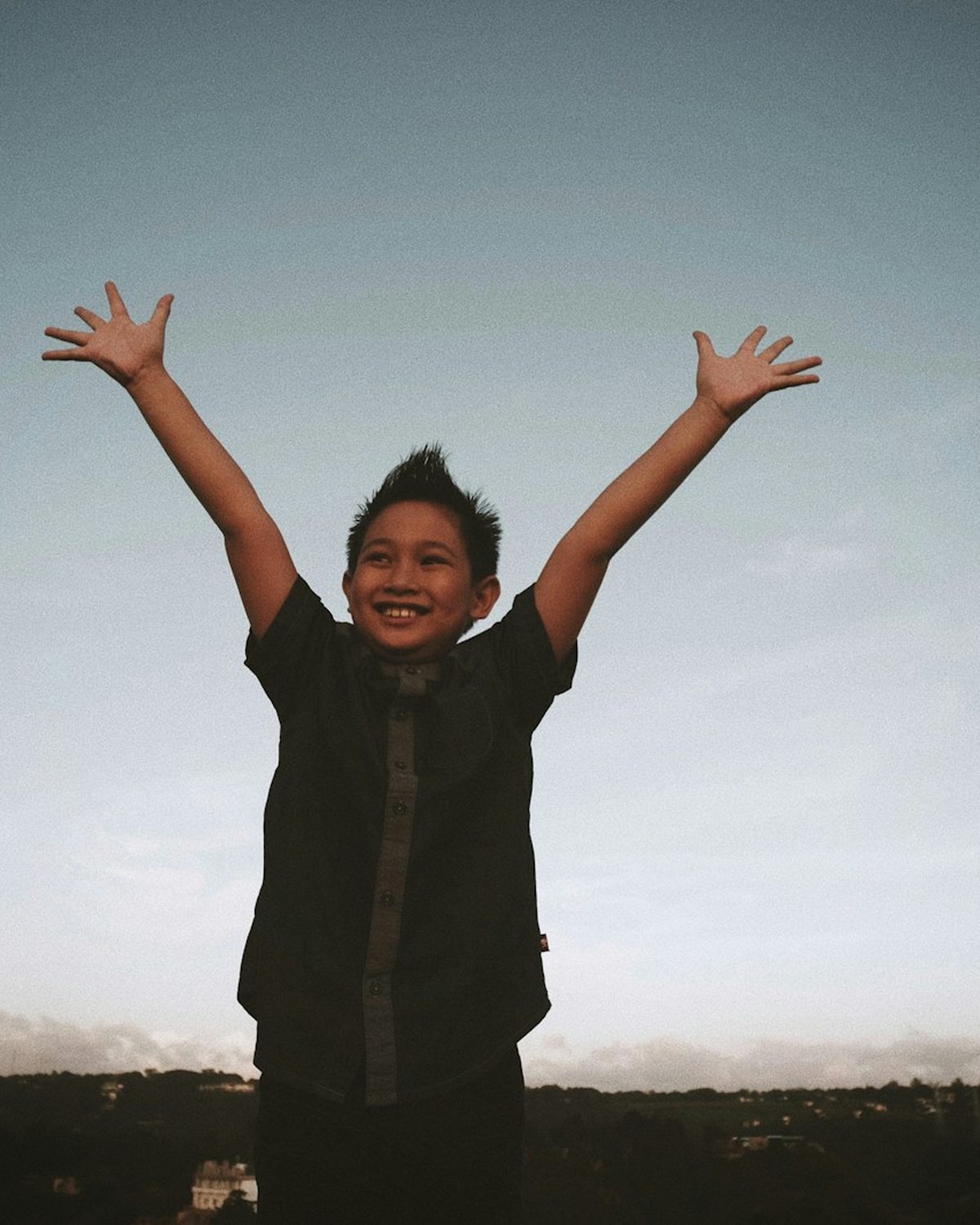 A young child celebrating with both hands raised in the air