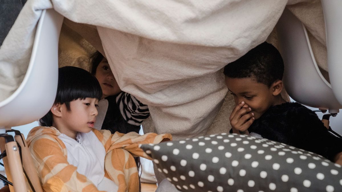 Children playing inside a blanket fort at home
