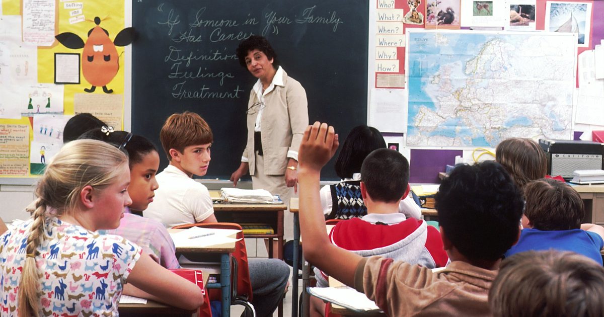 A teacher standing in front of a group of young school children in a classroom