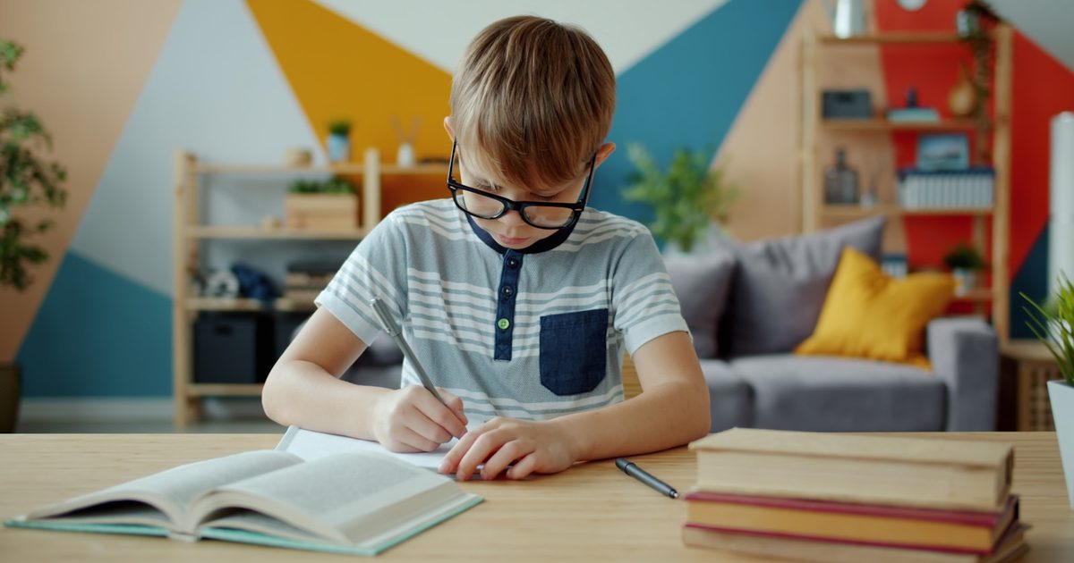 A left-handed child writing at a desk