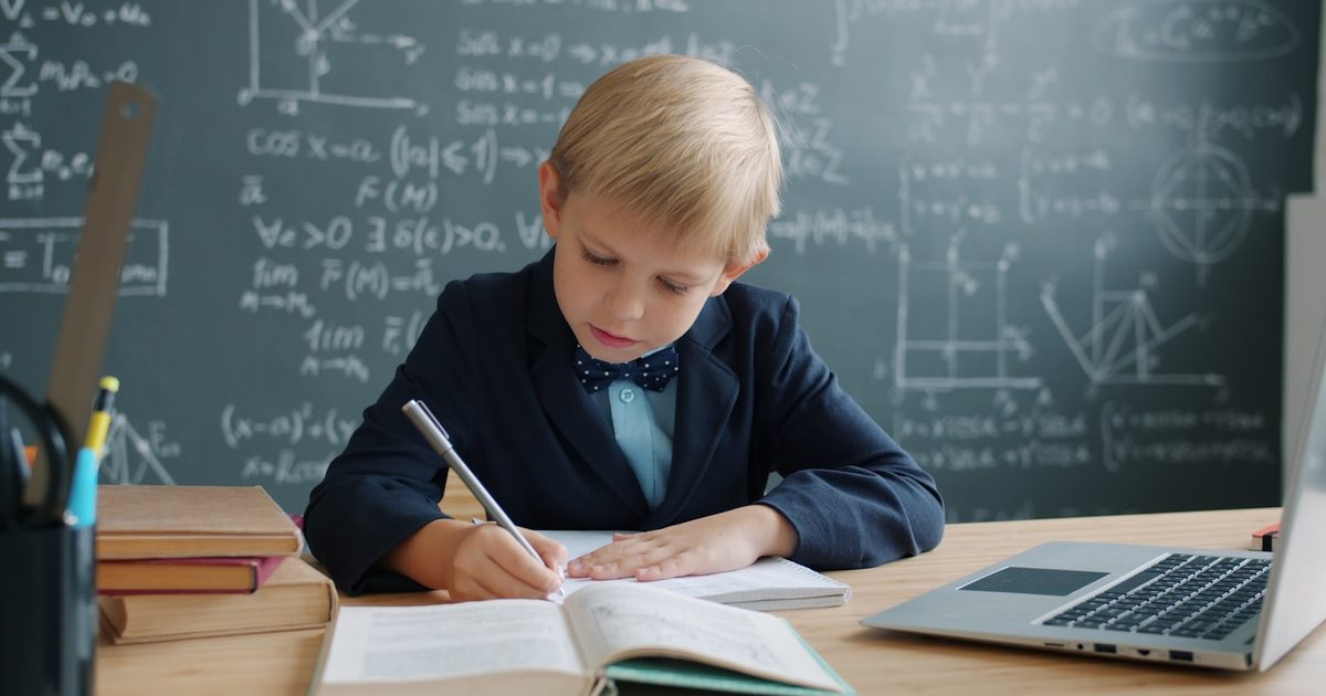 A child working through maths problems at a desk at home