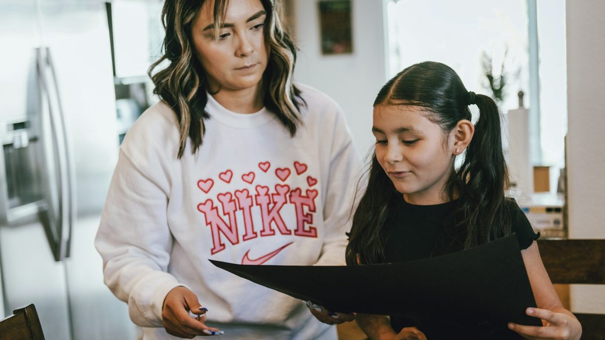 A parent sitting with a child and helping with homework