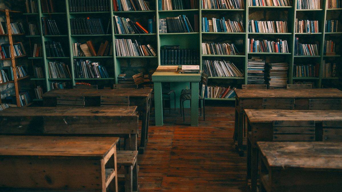 A nostalgic old school classroom with wooden desks and shelves of books