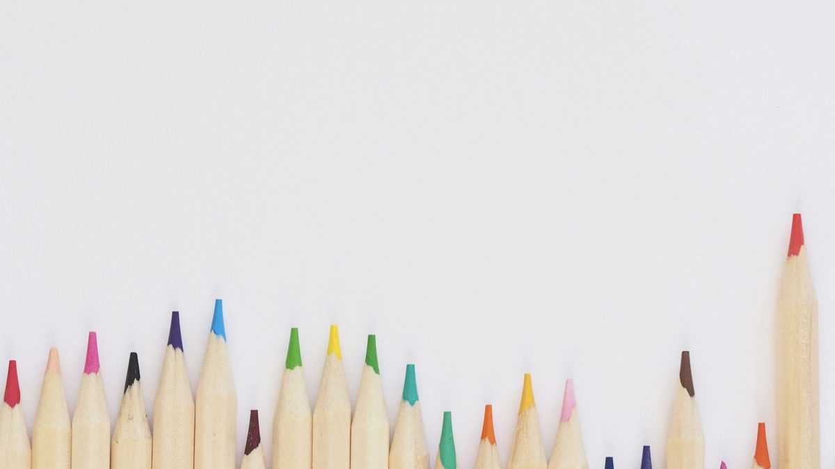 Sharpened coloured pencils lined up in a neat row on a white surface