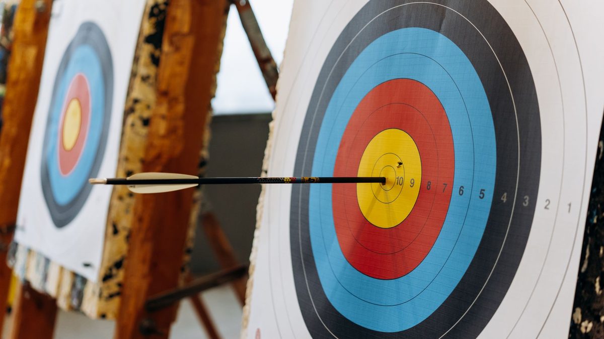 A pencil positioned pointing towards a target on a desk