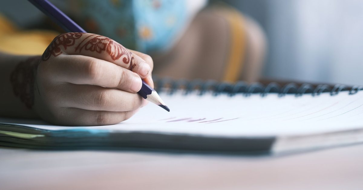 A child holding a pencil and writing in a notebook