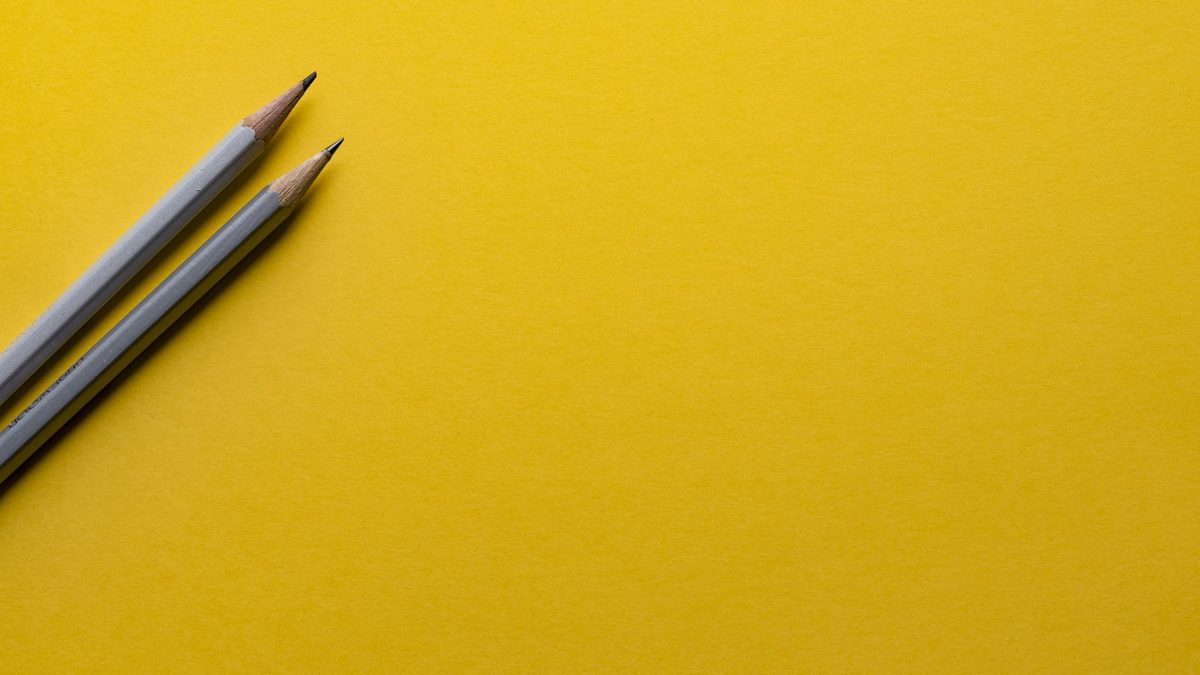 Two pencils positioned facing each other on a bright surface, representing a matchup