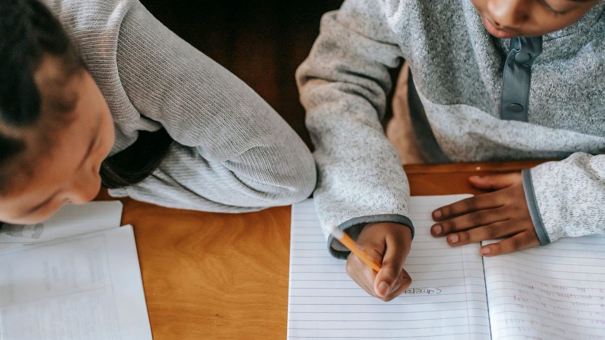 Two children writing side by side at their school desks