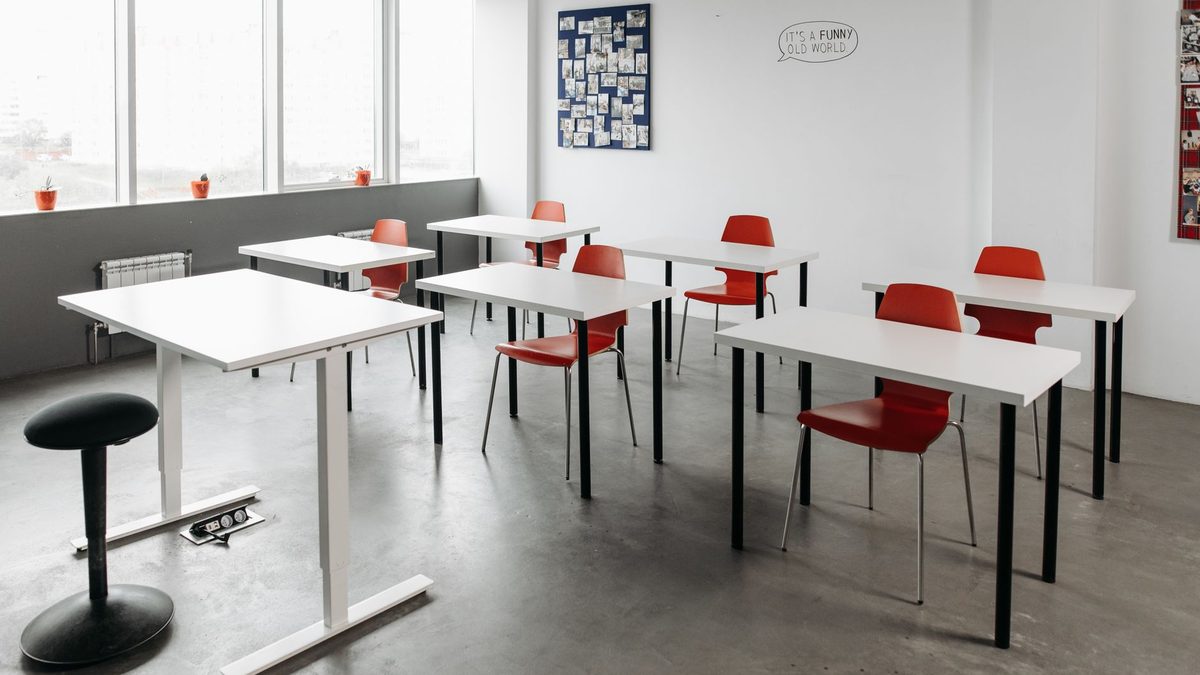 A small classroom filled with desks leaving little clear floor space
