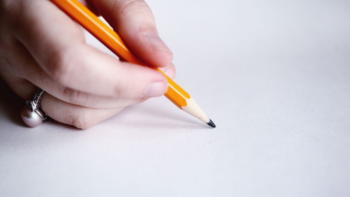 A hand curled awkwardly into a hooked position while writing