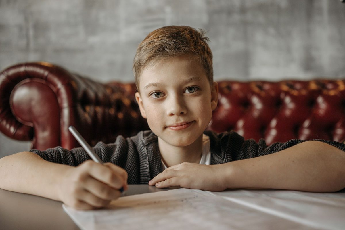 A boy pausing with a pencil in hand while working at a table