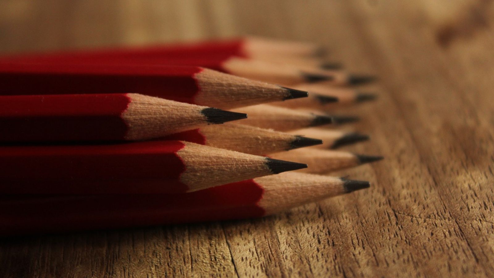 Sharpened red pencils gathered points together on a wooden desk