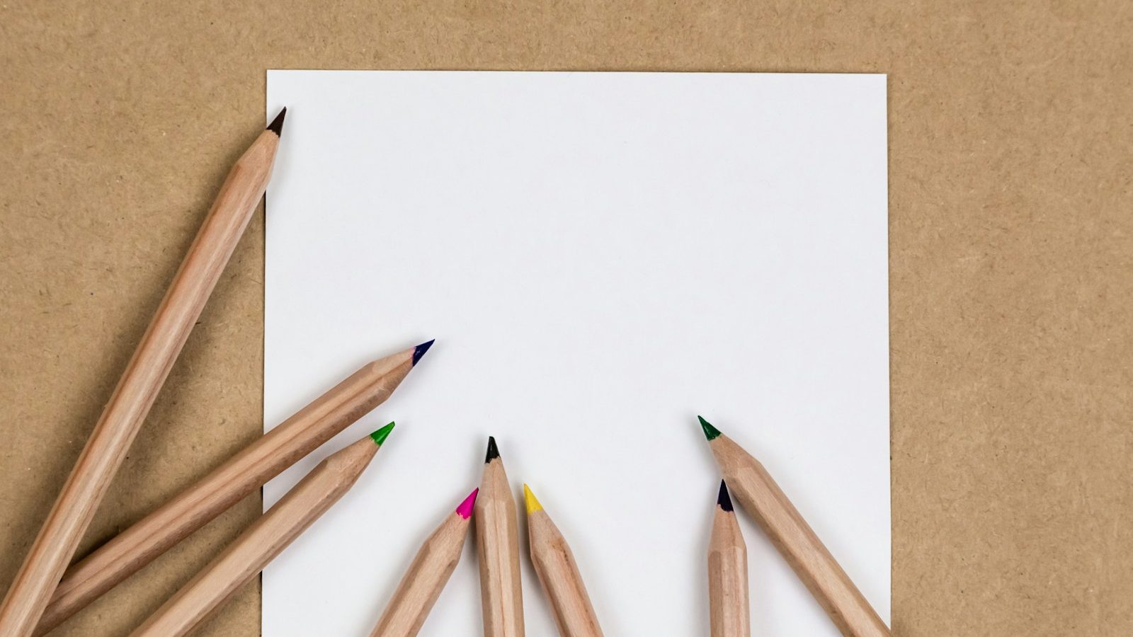 Plain wooden pencils laid out in a fan across a sheet of paper