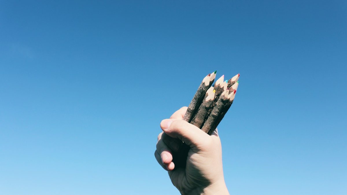 Fingers gripping a pencil higher up the barrel